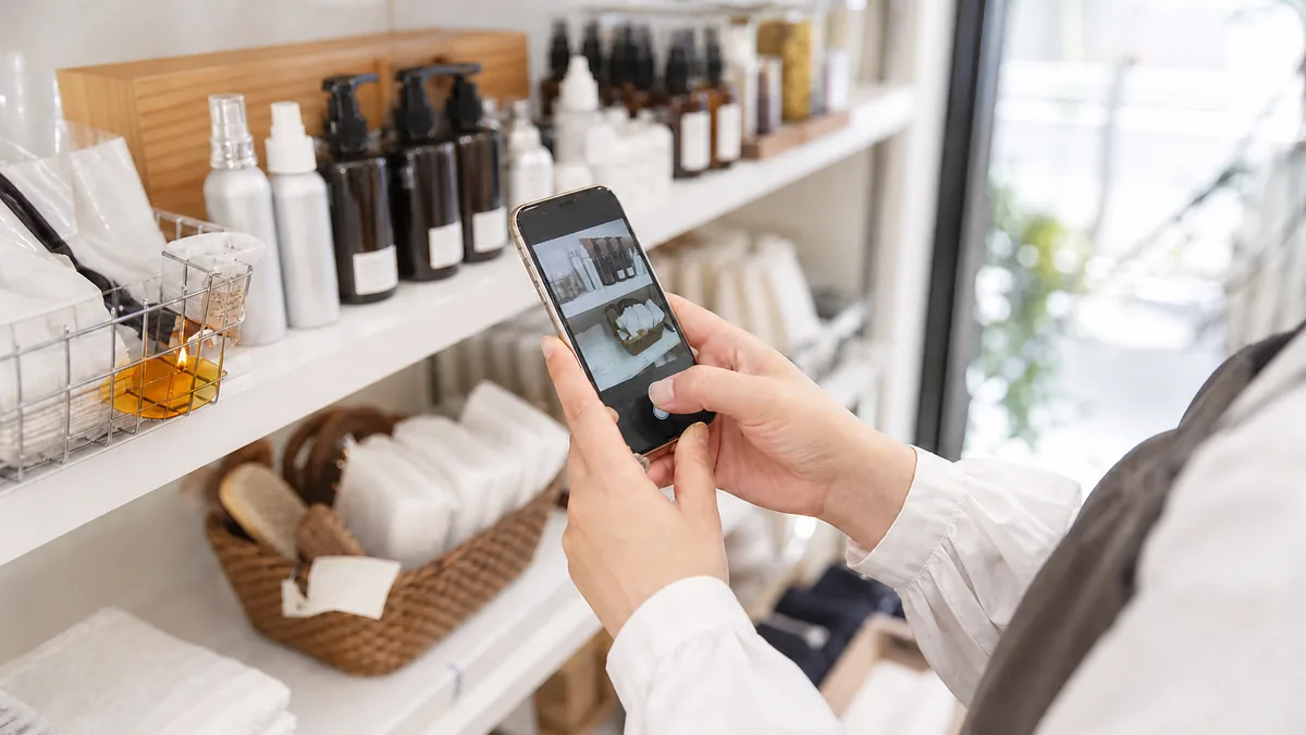 店内の商品棚をスマートフォンで撮影する店舗スタッフの手元