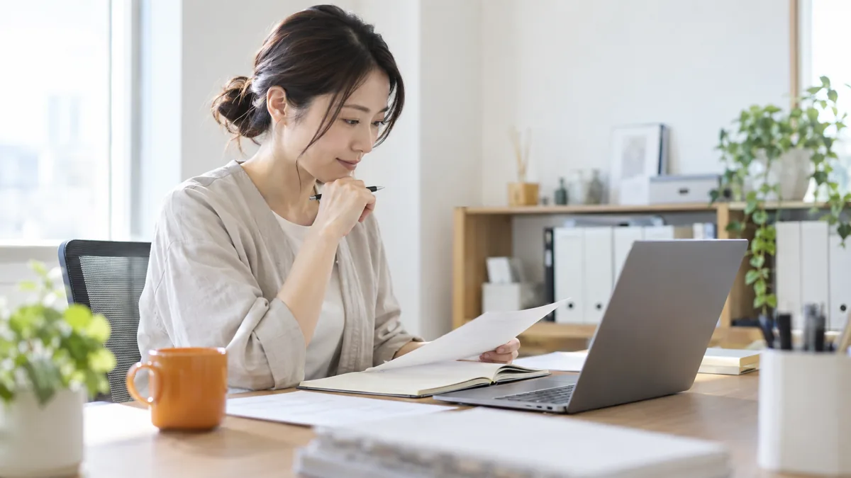 オフィスの机で制作会社との打ち合わせ資料を確認しながらサイトの目的を整理する経営者の写真